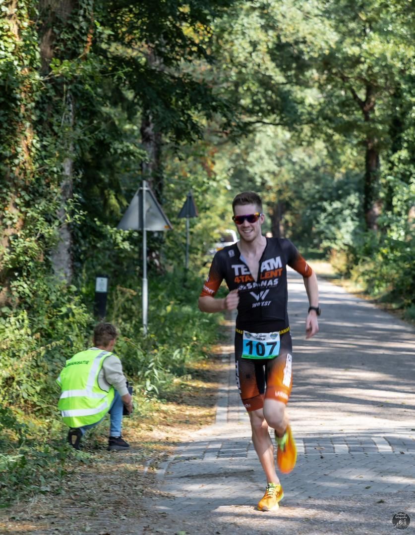 Een man rent over de weg met een startnummer 107 op