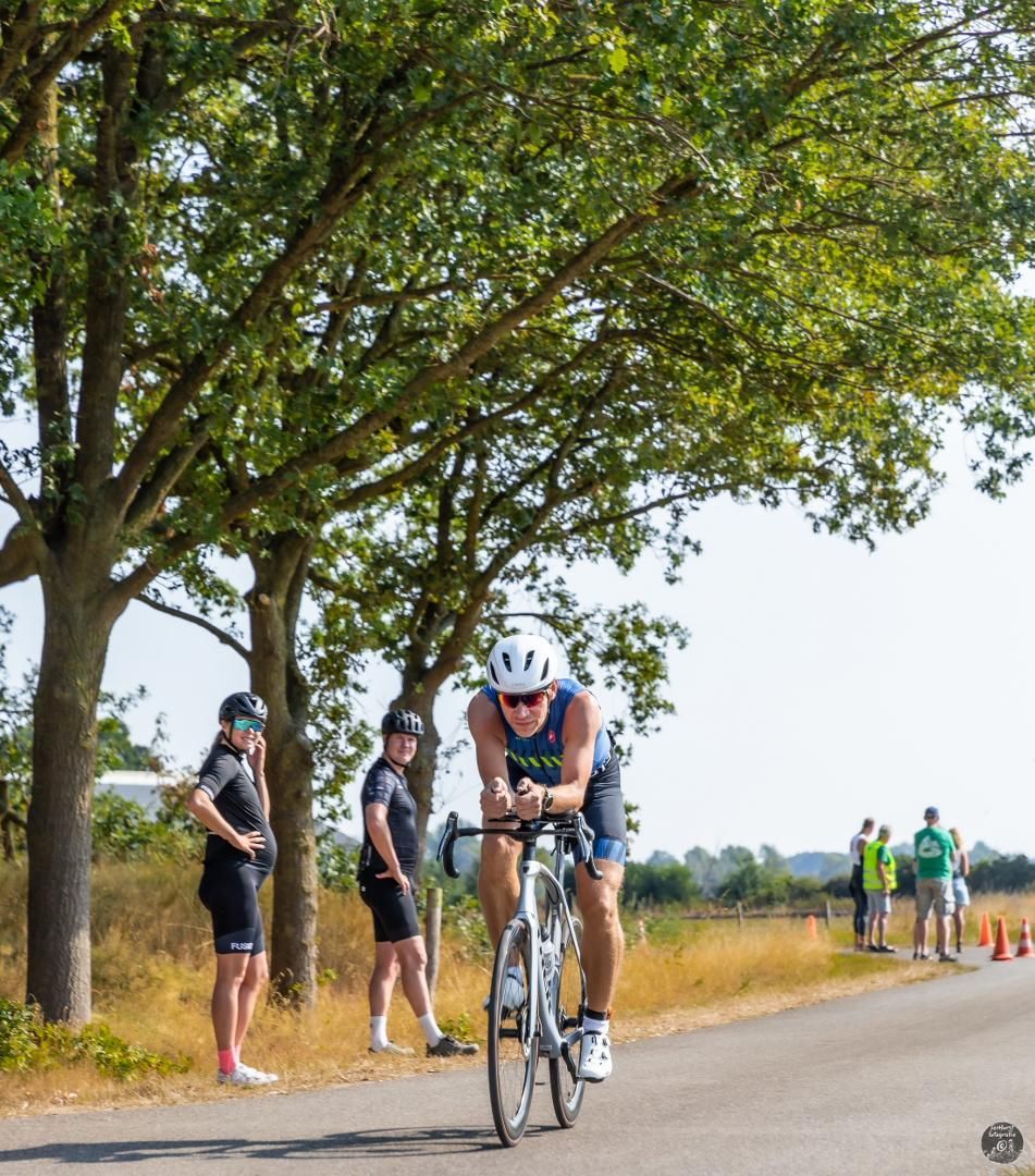 Een man fietst over een weg met bomen op de achtergrond