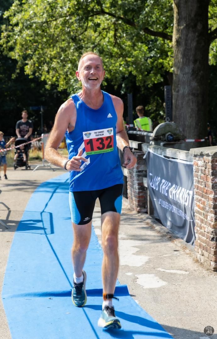 Een man in een blauw tanktopje en korte broek rent op een blauwe mat.