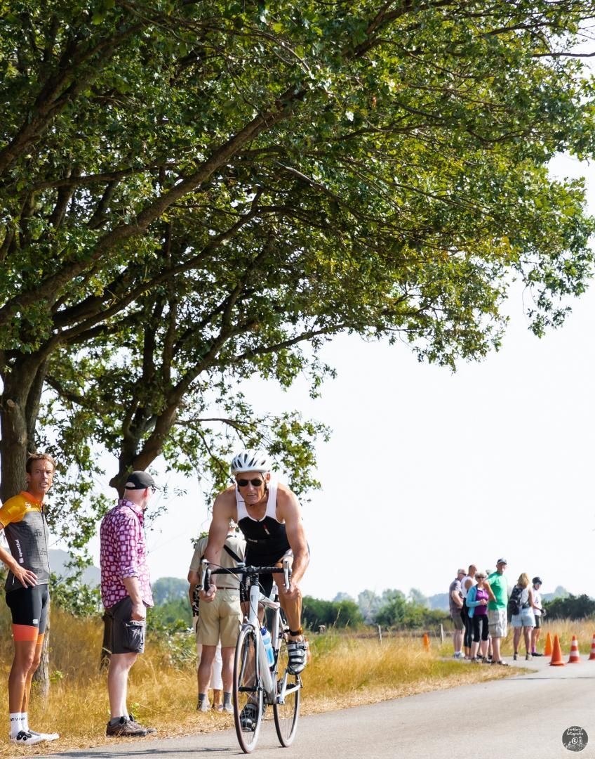 Een man fietst over een weg terwijl mensen kijken