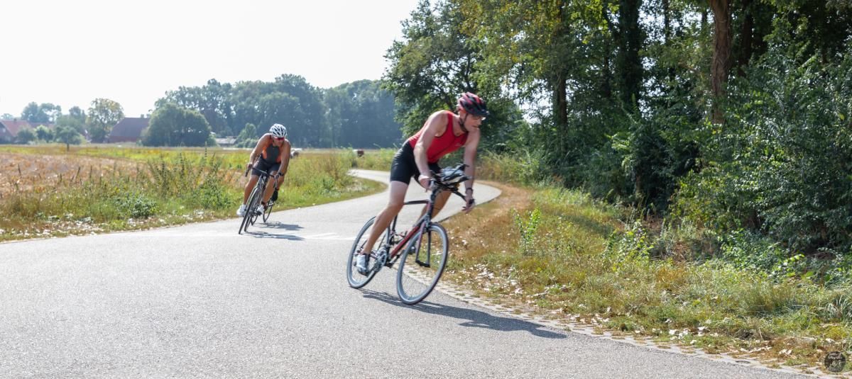 Twee mensen fietsen over een weg.