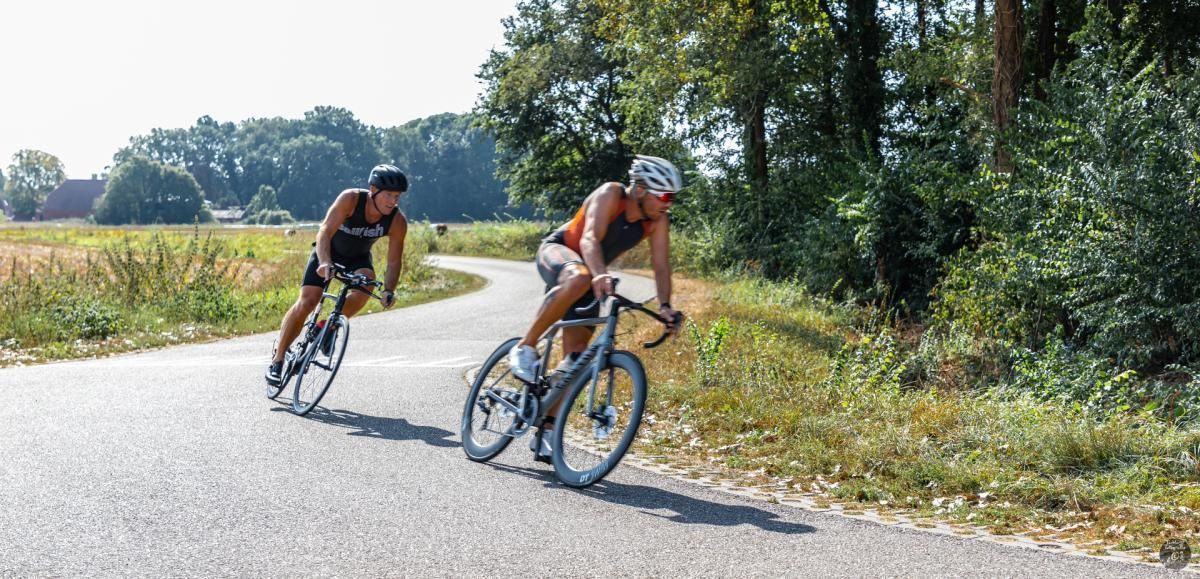 Twee mensen fietsen over een weg.