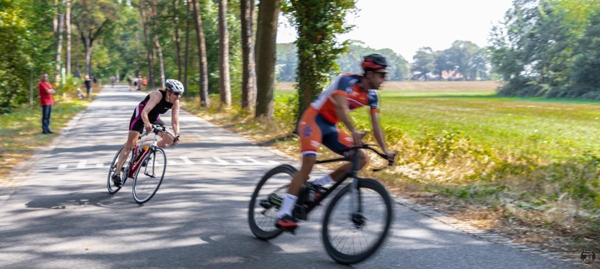 Twee mensen fietsen over een weg.