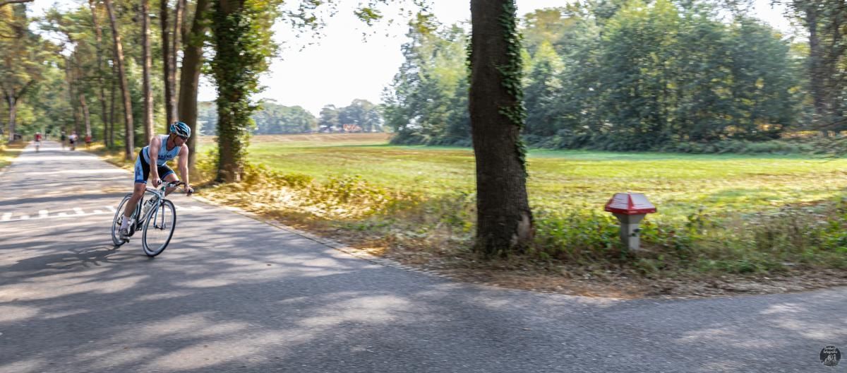 Een man fietst over een weg naast een brandkraan.