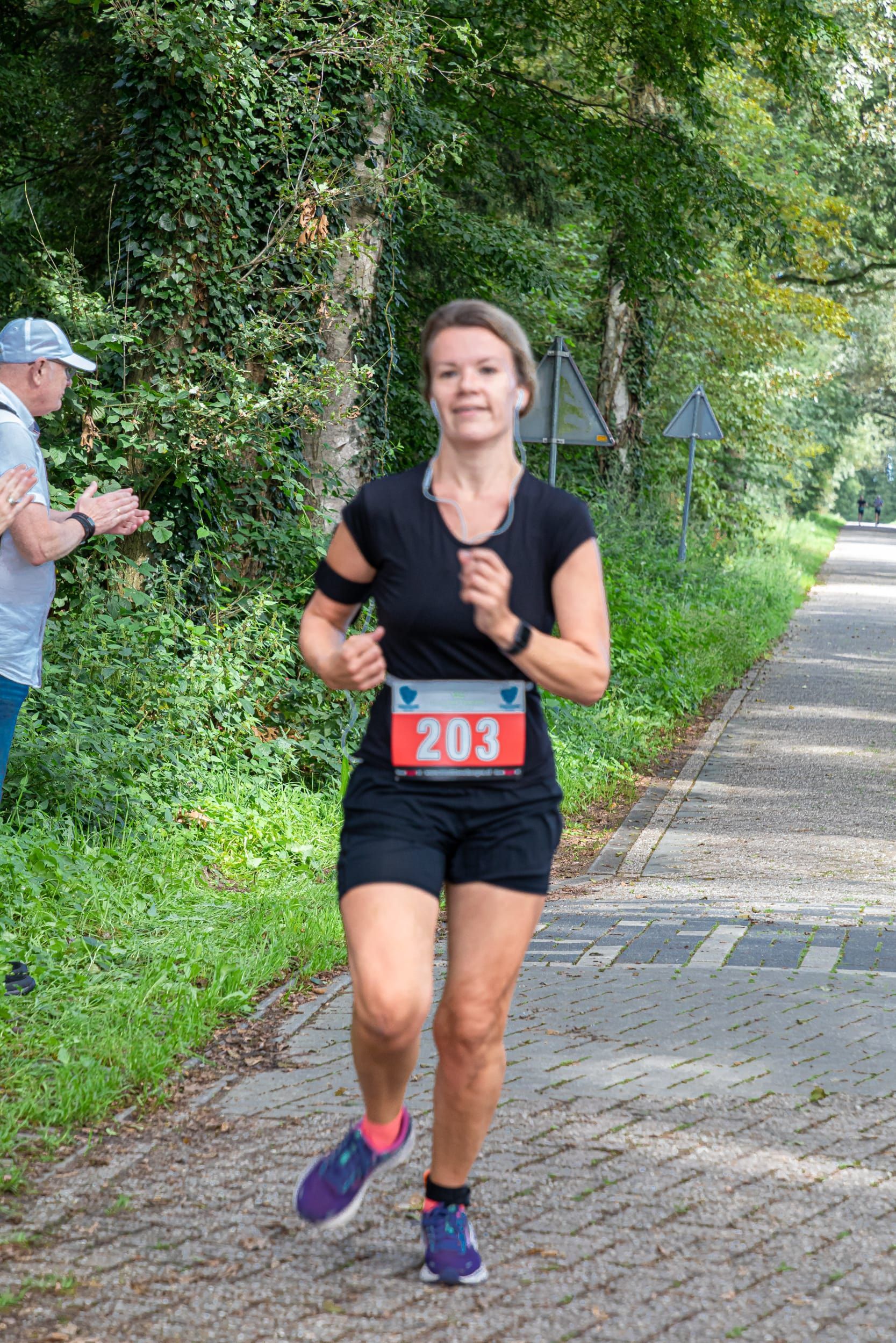 Een vrouw rent een marathon op een stenen weg.