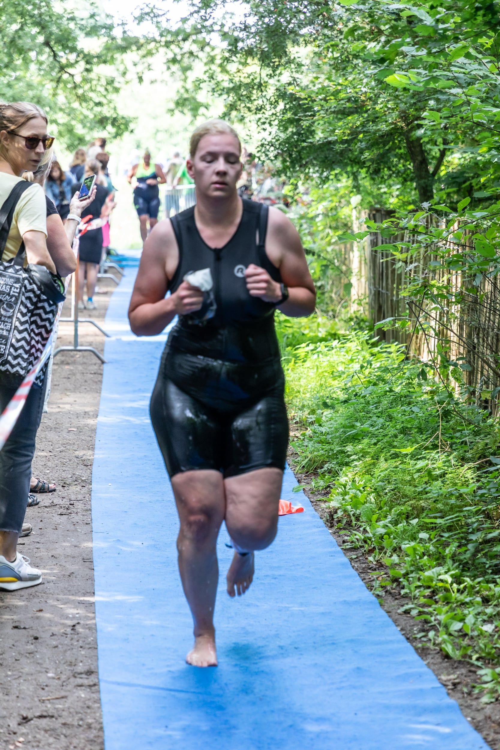 Een vrouw in een wetsuit rent op een blauwe mat.