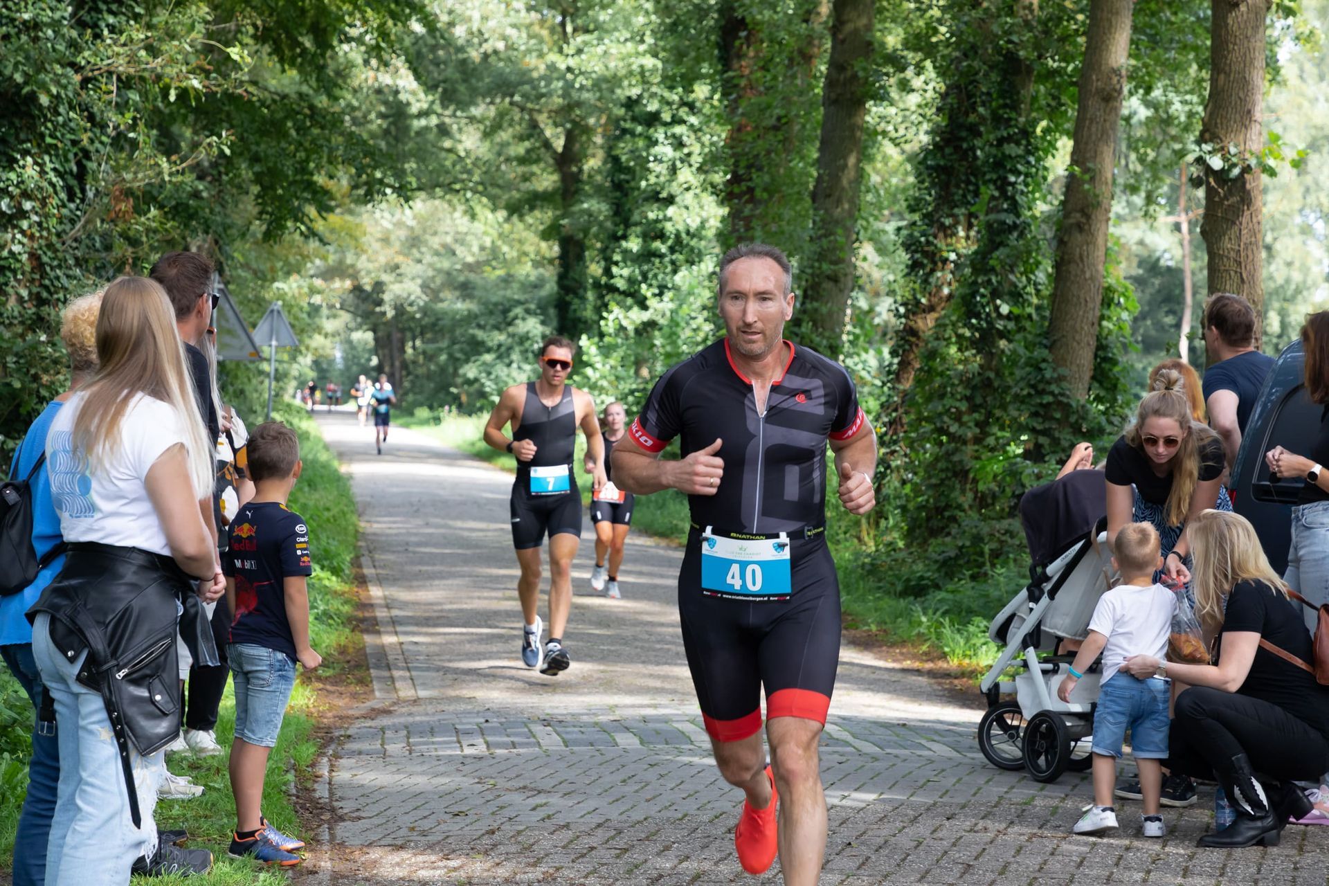 Een groep mensen kijkt naar een man die meedoet aan een triatlon.