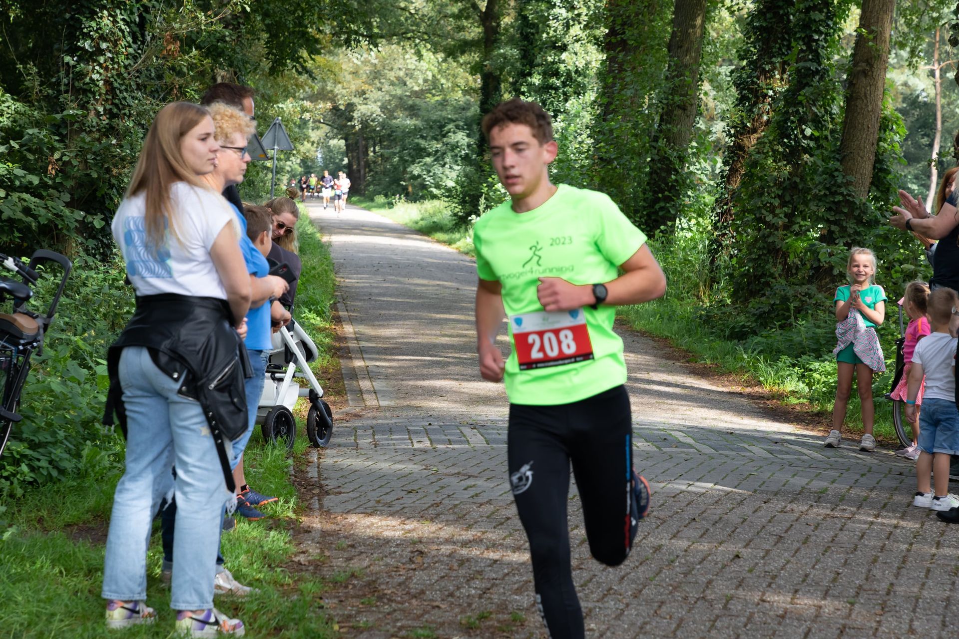 Een man in een groen shirt rent over een stenen weg.