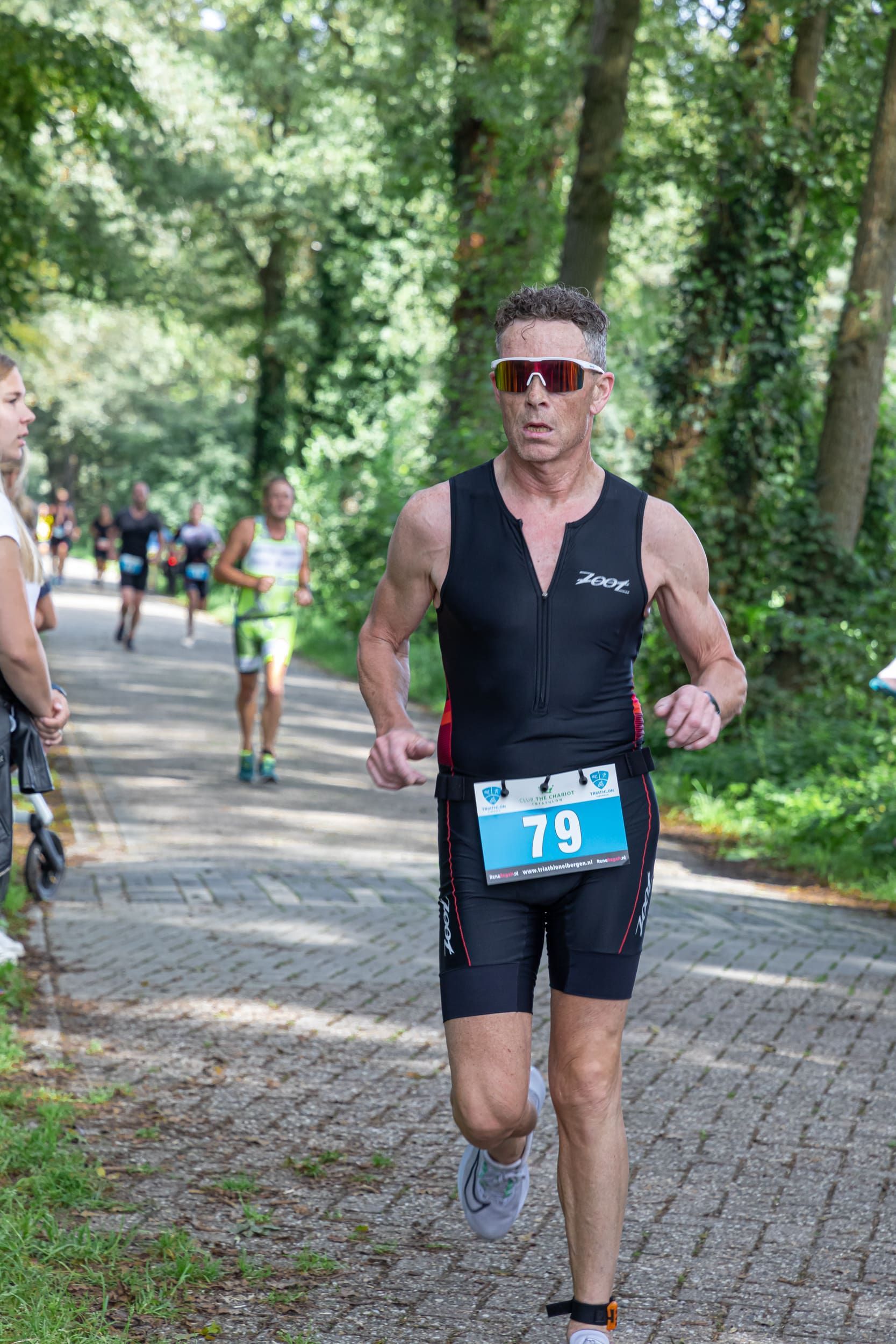 Een man rent mee in een triatlon op een stenen weg.