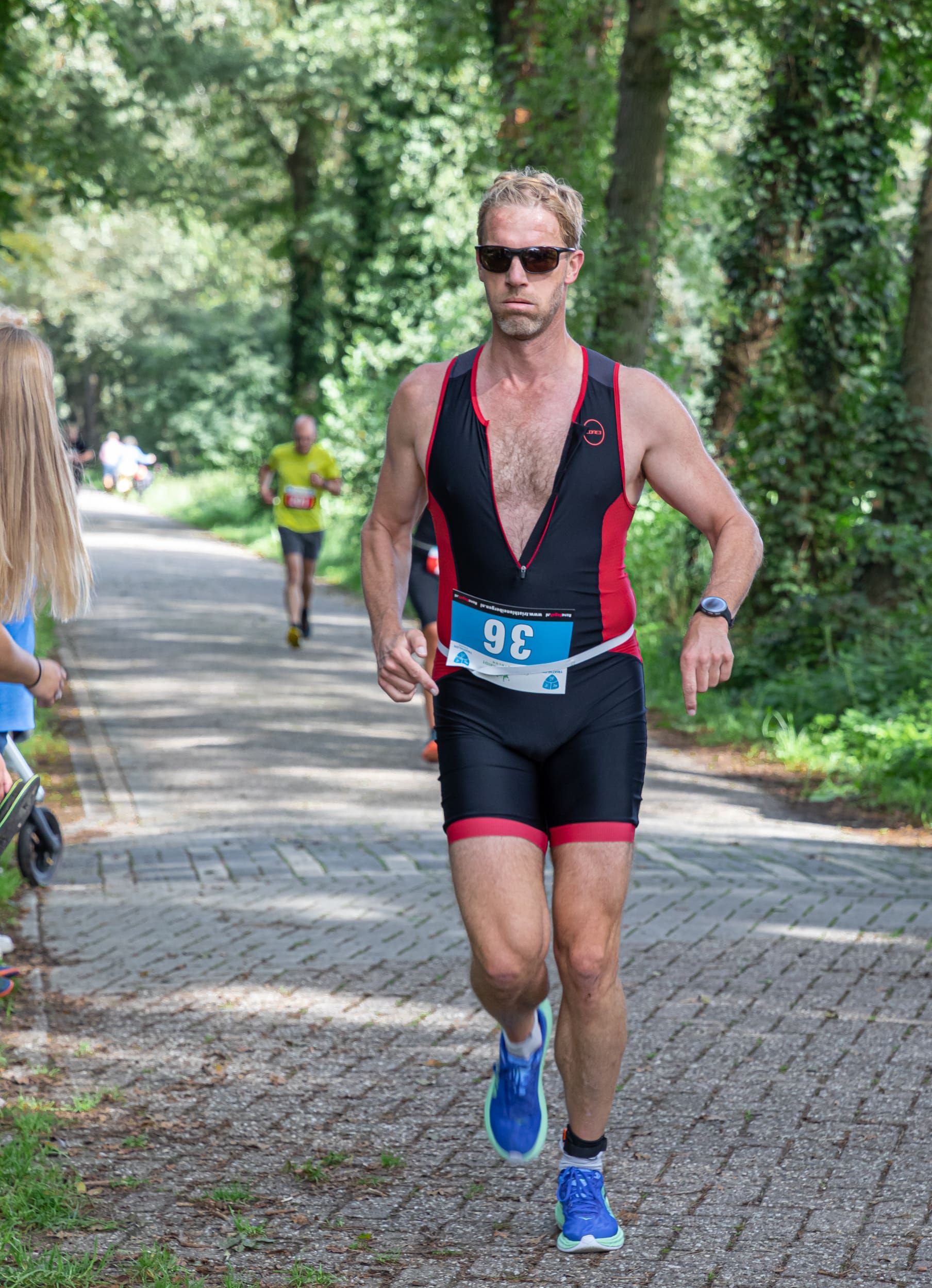 Een man rent mee in een triatlon op een stenen weg.