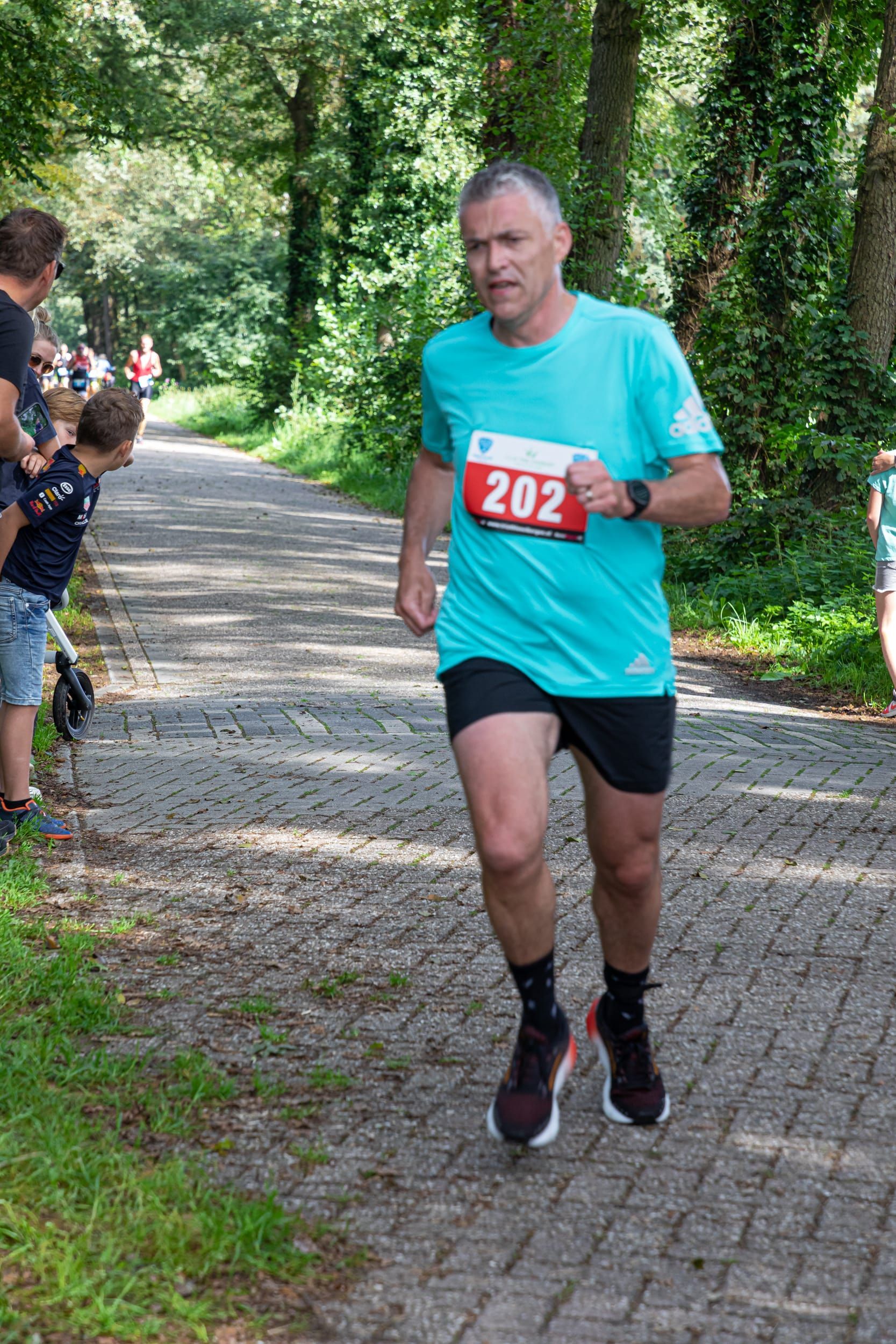 Een man rent een race op een geplaveide weg.