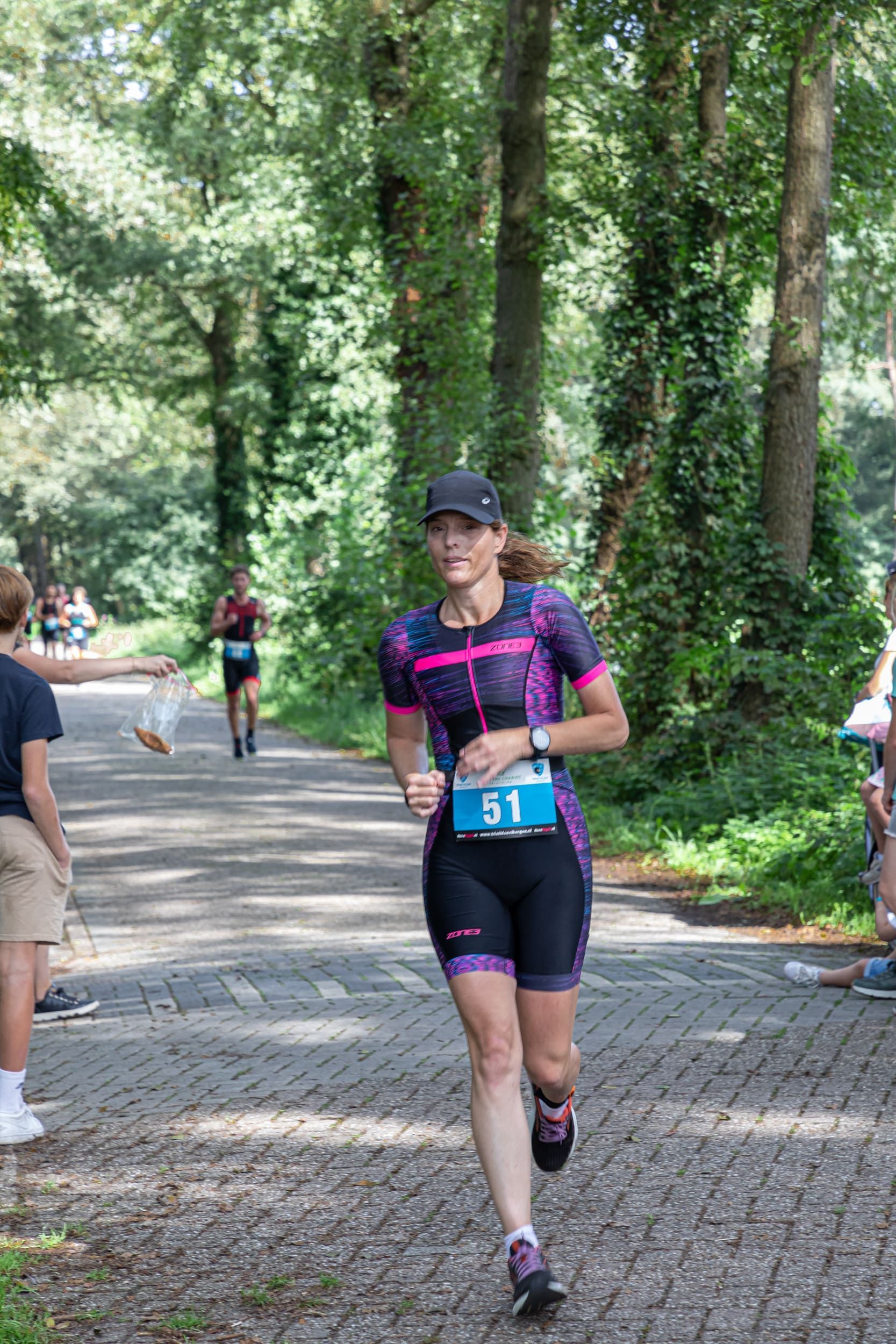 Een vrouw rent over een weg in het bos.