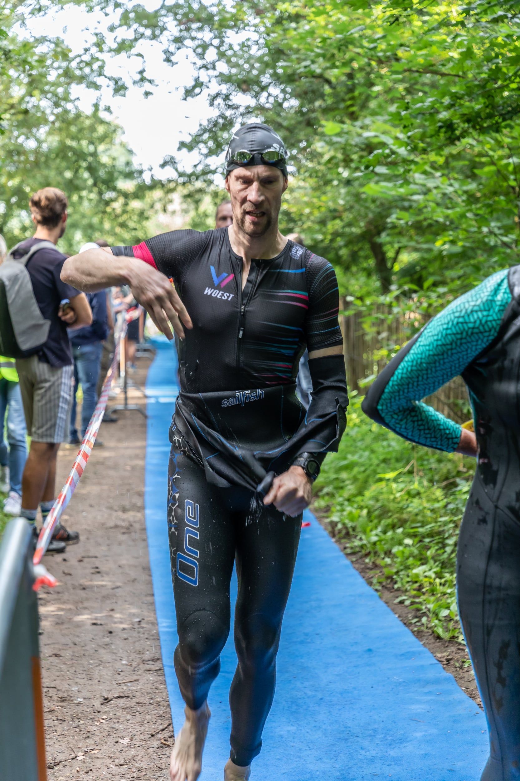 Een man in een wetsuit loopt over een pad.