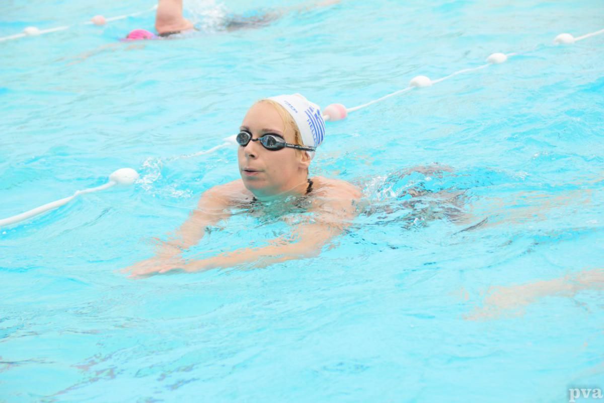 Triathlon Eibergen. Een vrouw zwemt in een zwembad met een badmuts en een zwembril op.