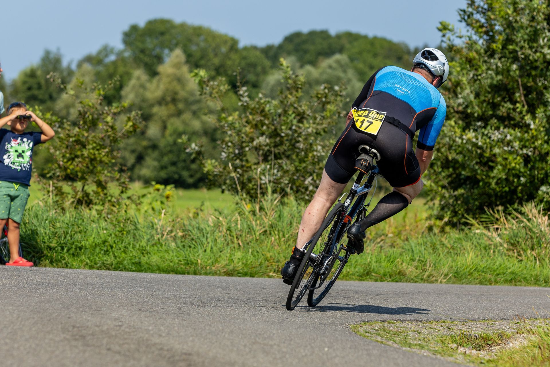 Een man fietst over een weg terwijl een jongen toekijkt.
