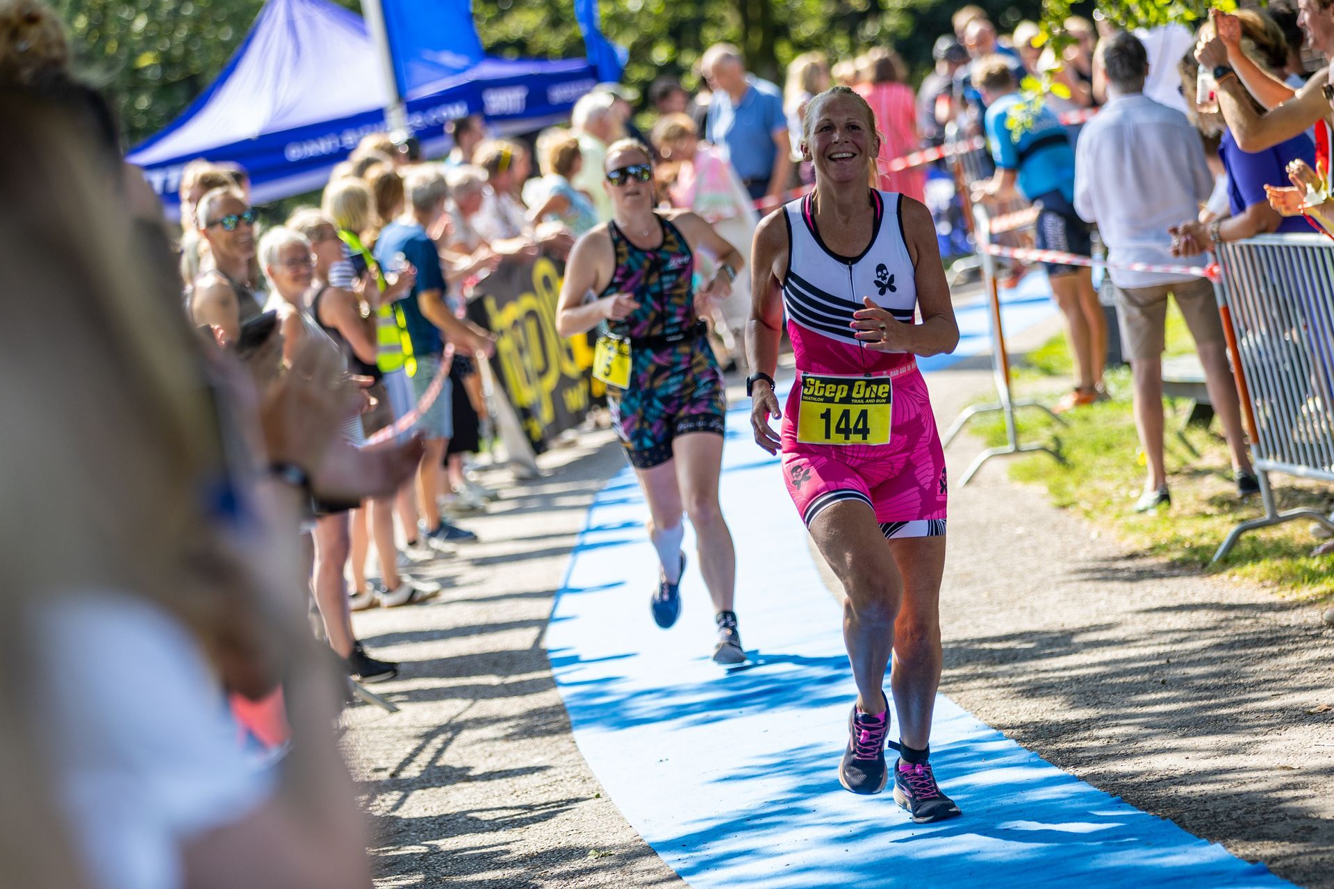 Een vrouw rent een marathon voor een grote groep mensen.