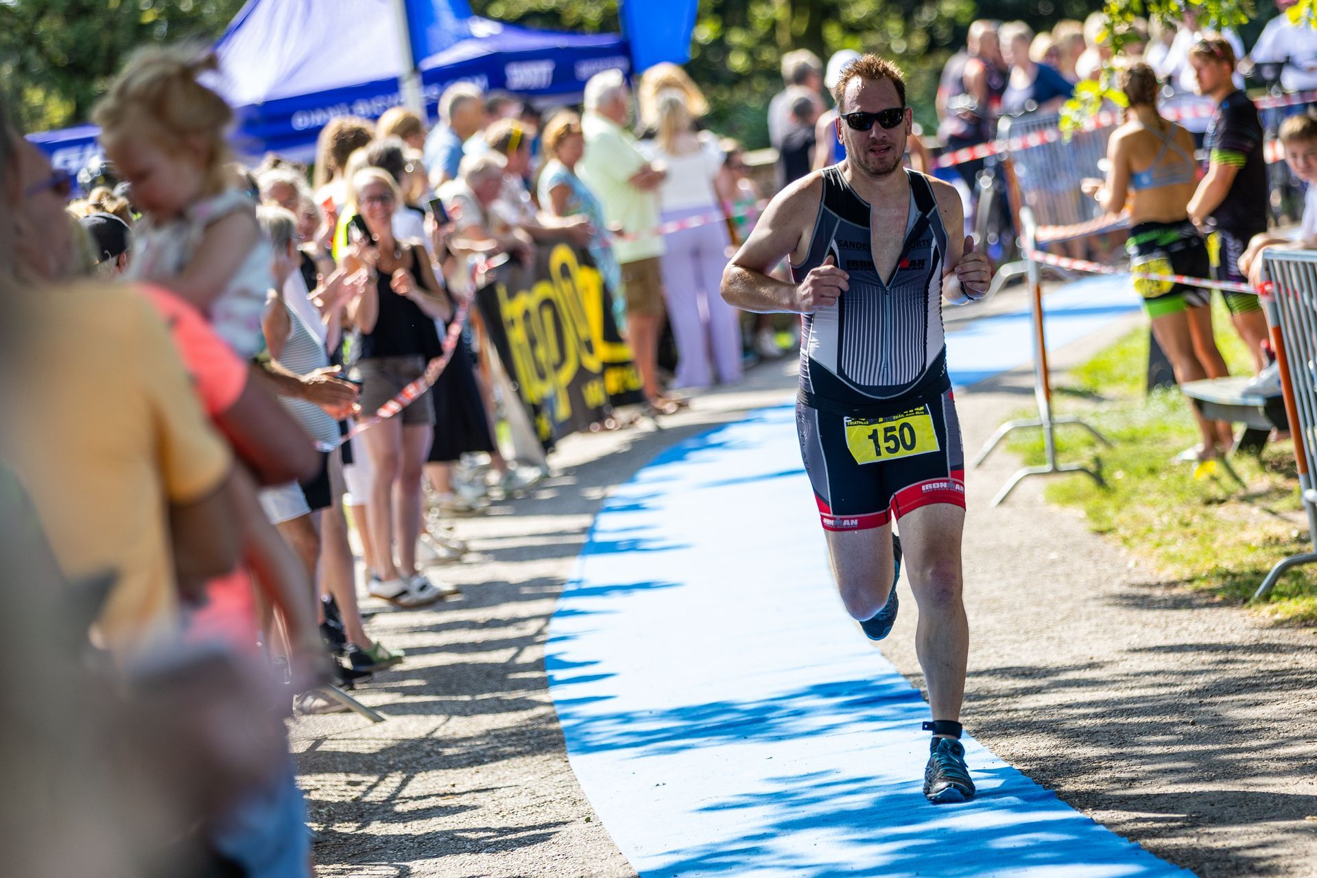 Een man rent op een blauwe loper tijdens een triatlon.