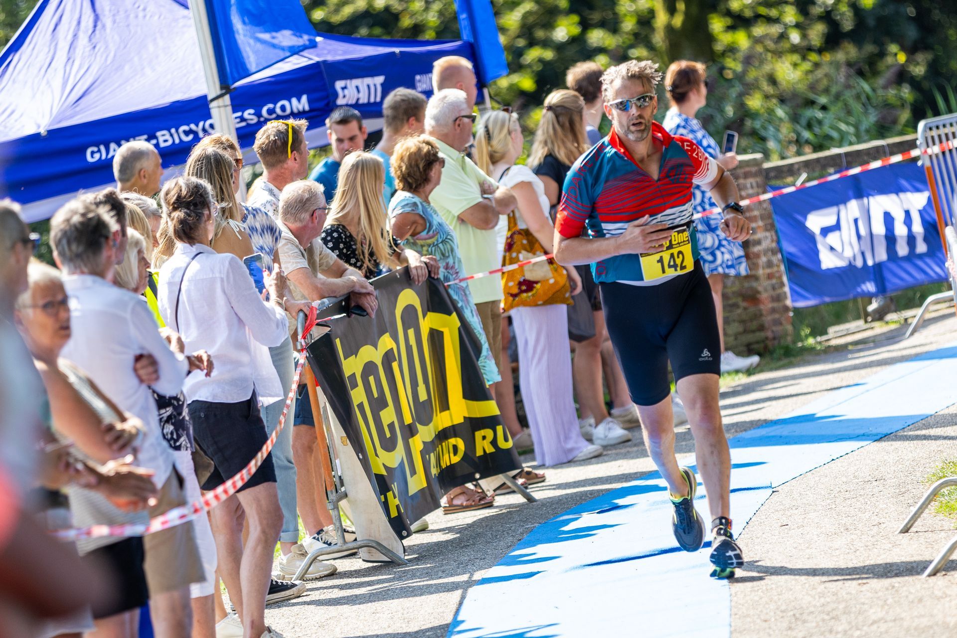Een man rent een marathon voor een grote groep mensen.