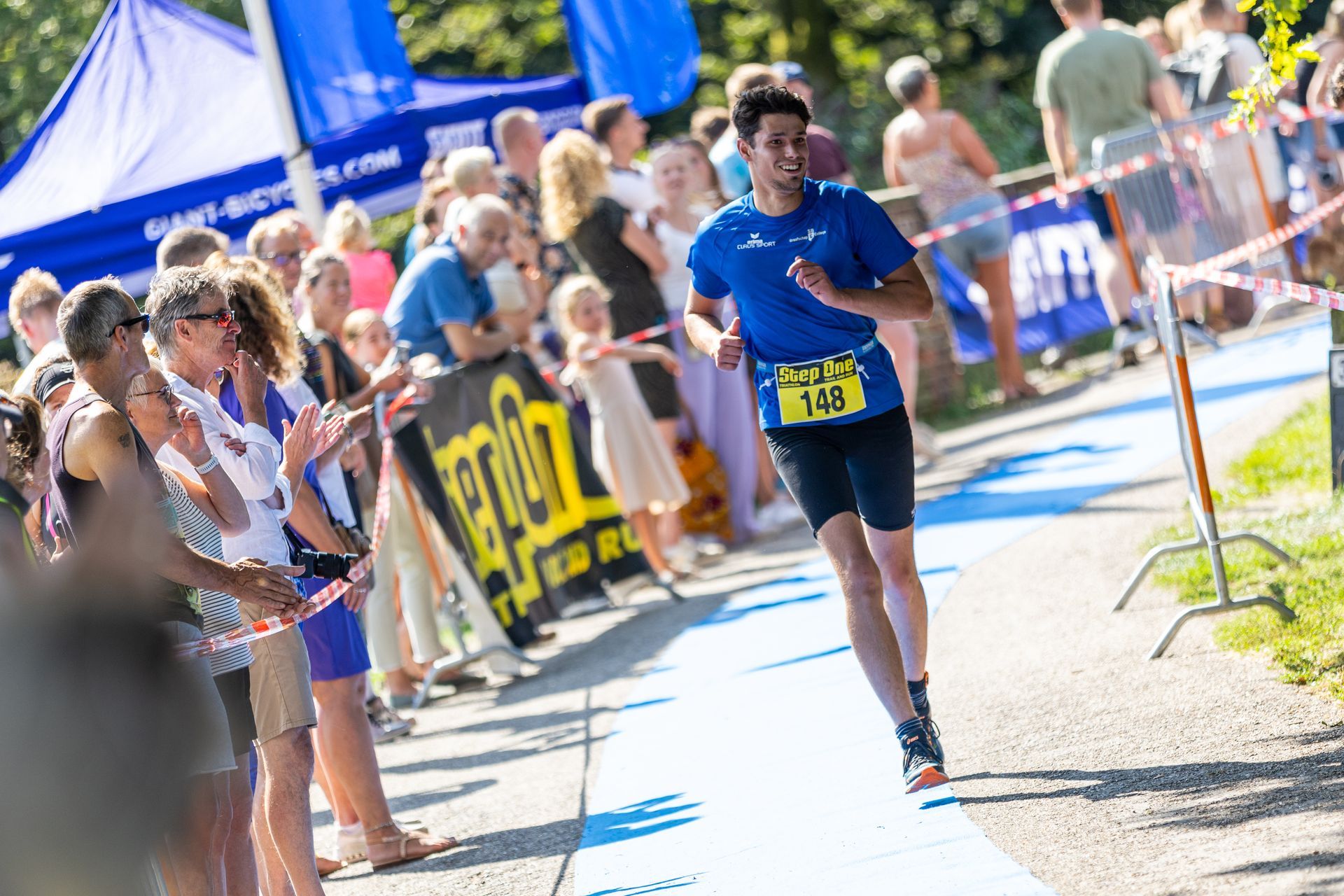 Een man rent een marathon voor een grote groep mensen.