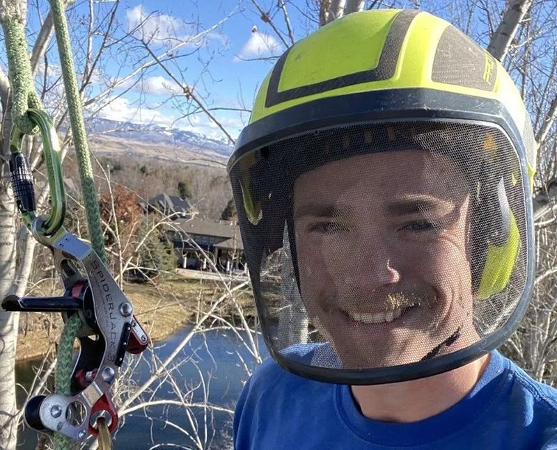 A man wearing a yellow helmet and a blue shirt is smiling.