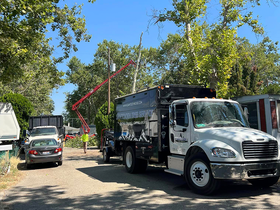 A white truck with a crane attached to it is parked on the side of the road.