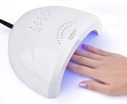 Mano bajo lámpara UV blanca para uñas con luz azul