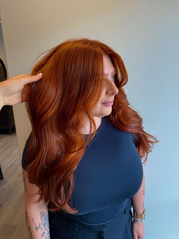 Curling iron styling brown hair in a salon.