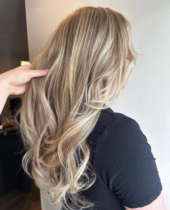 Curling iron styling brown hair in a salon.