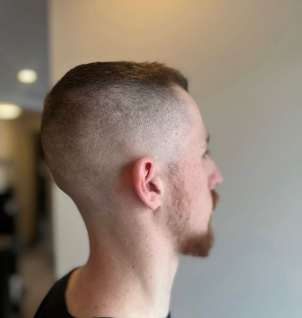 Curling iron styling brown hair in a salon.