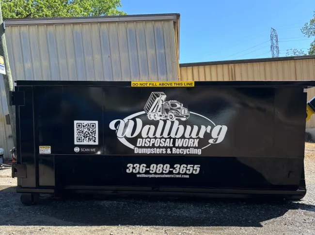 A dumpster with the word wallburg on it is parked in front of a building.