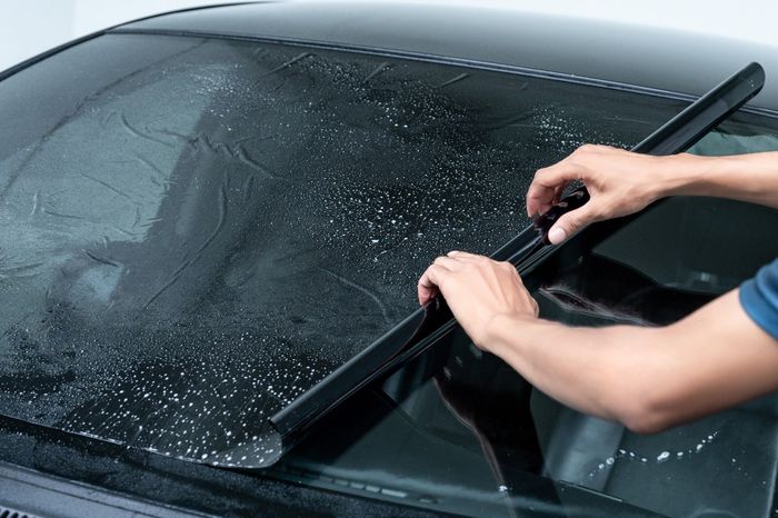 A person is cleaning the windshield of a car with a wiper blade.