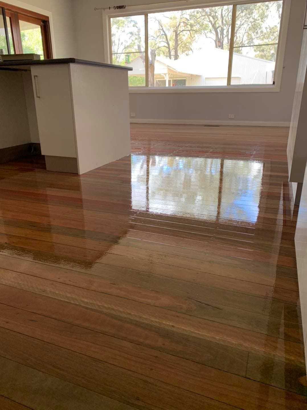 Newly Polished Kitchen Floor  with a Shelve and Window In Background — Floor Sanding in Kearneys Spring, QLD