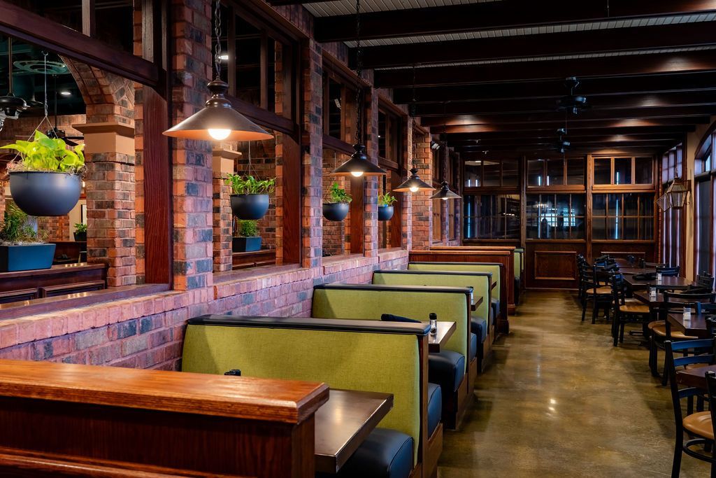 Empty restaurant interior with wooden booths, brick walls, and hanging pendant lights