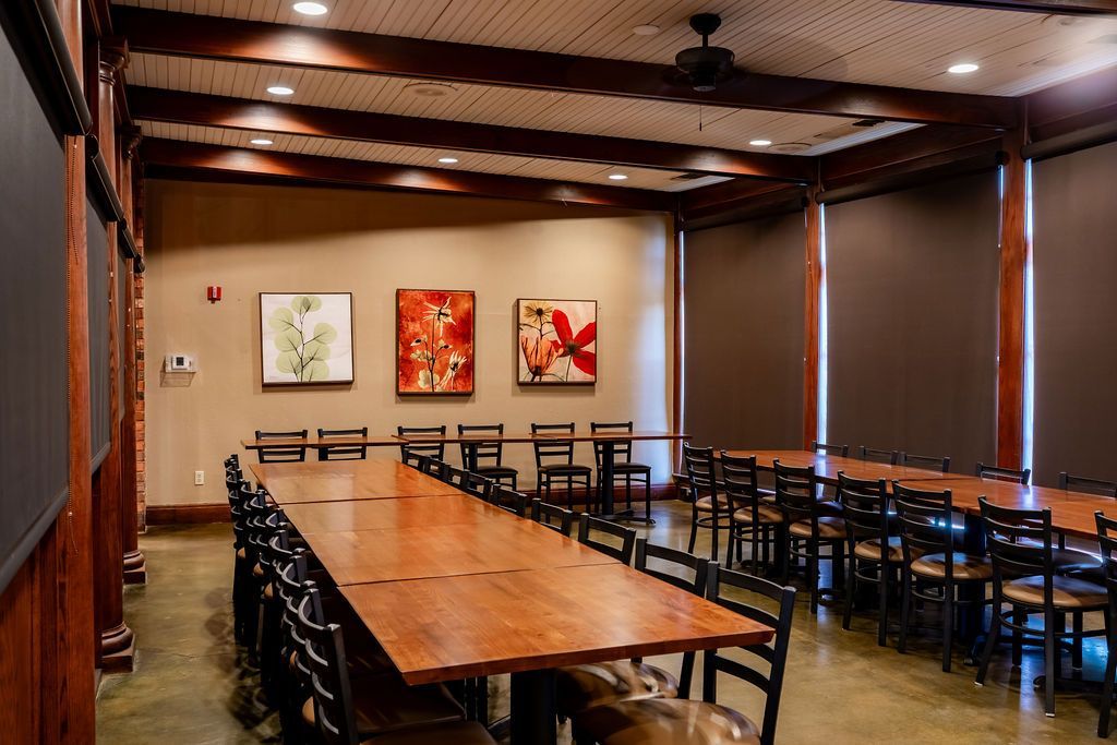 Conference room with a long wooden table, rows of black chairs, and wall art under warm lighting