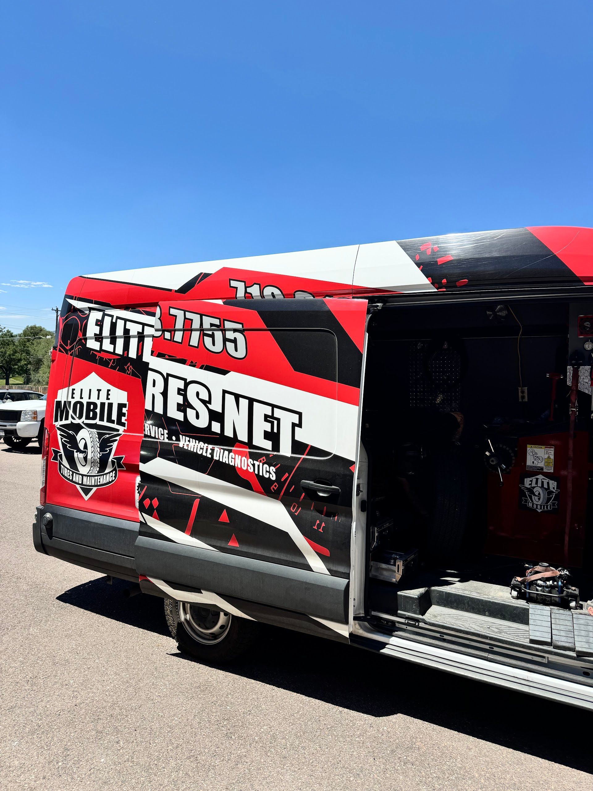 Red and white mobile service van with an open side door on a sunny day. | Elite Mobile Tires and Maintenance