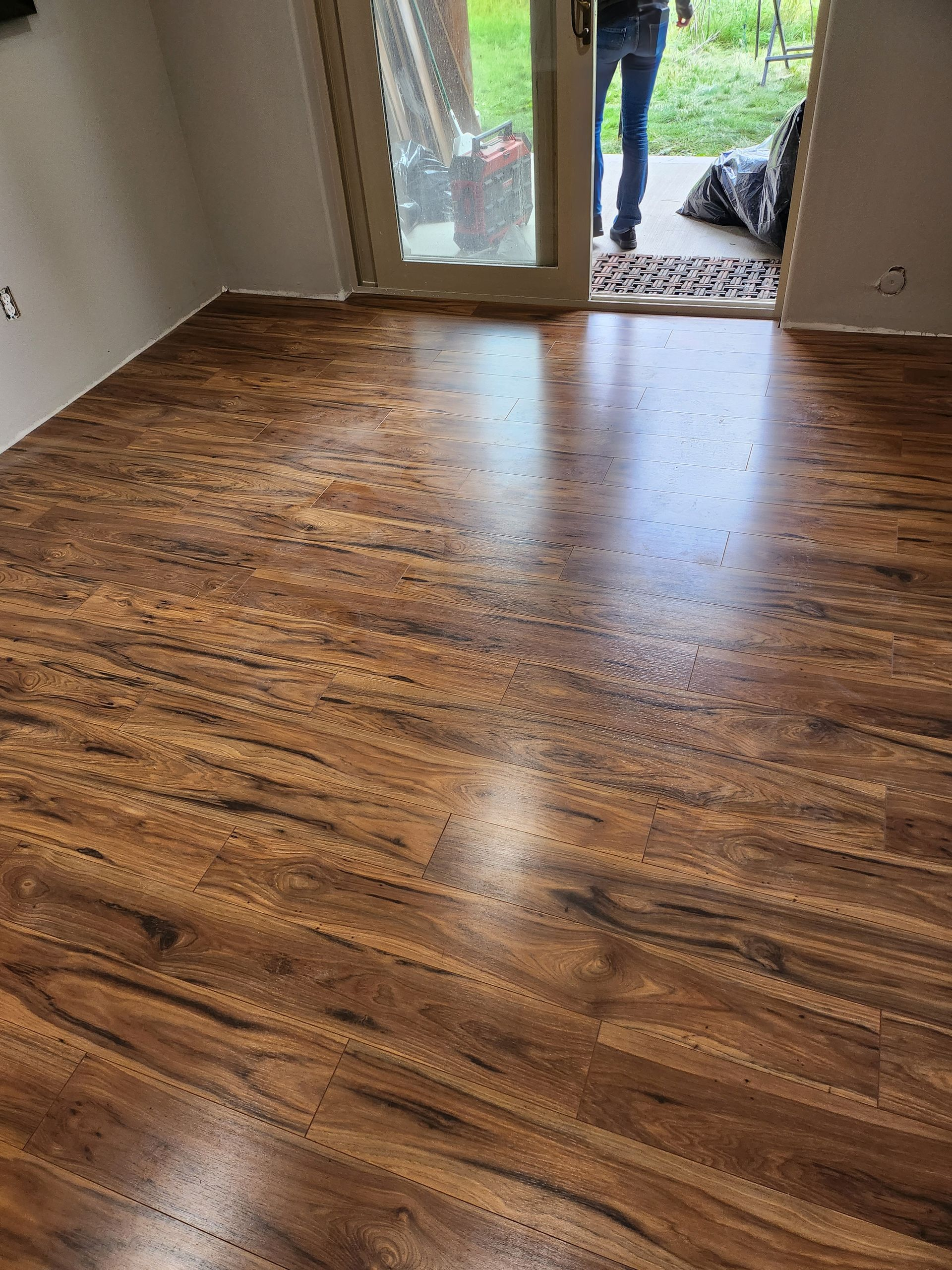 Hardwood-style laminate flooring in a room with a glass door leading outside.