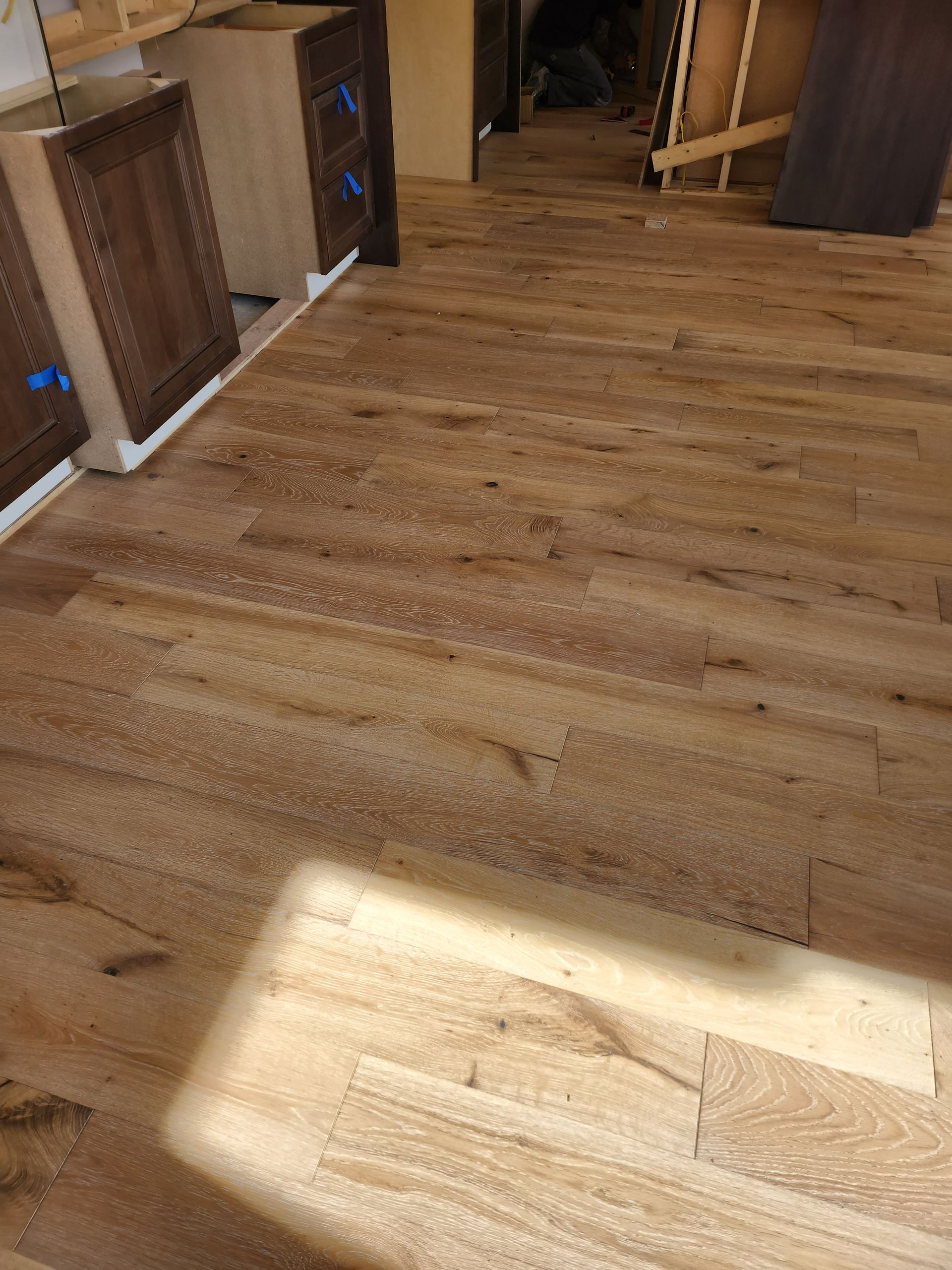 Wooden floor with cabinets in background, light brown color, indoor setting.