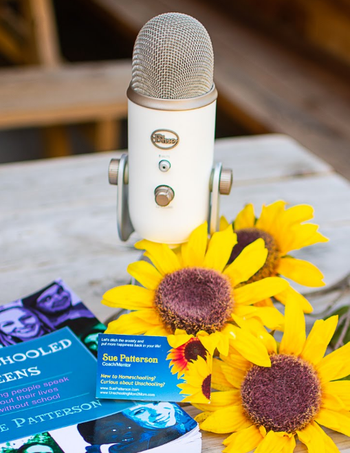 White microphone, sunflowers, book, and business cards on a wooden surface.
