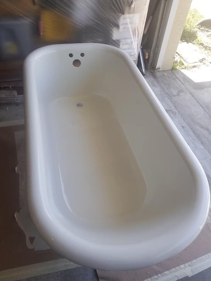 A white, oval-shaped bathtub sits on a floor in a workshop or garage setting.