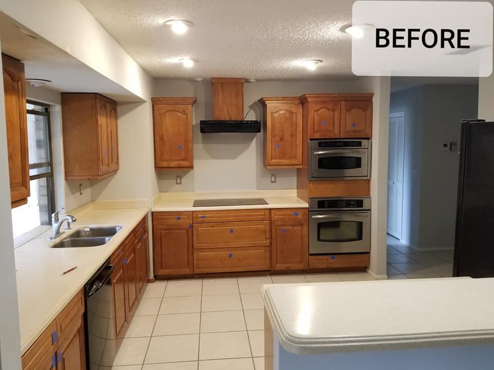 A kitchen featuring traditional wood cabinets, a black range hood, double wall ovens, and light countertops.