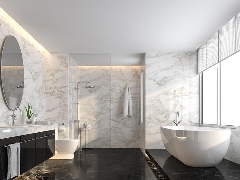 A luxurious bathroom with marble walls, a freestanding tub, black vanity, and a shower area with soft accent lighting.