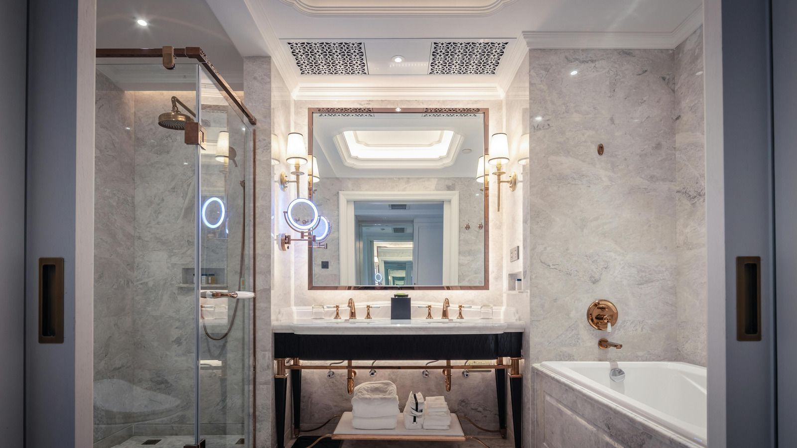 Luxurious bathroom with marble walls, double vanity, and glass shower.