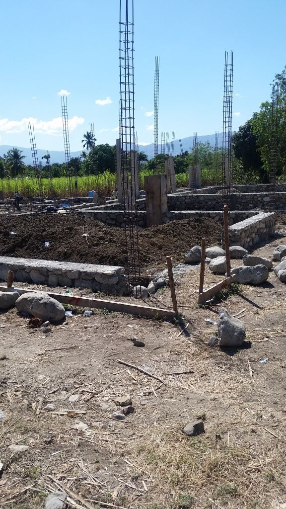 Construction site with stone foundation and rebar structures under a clear sky. 