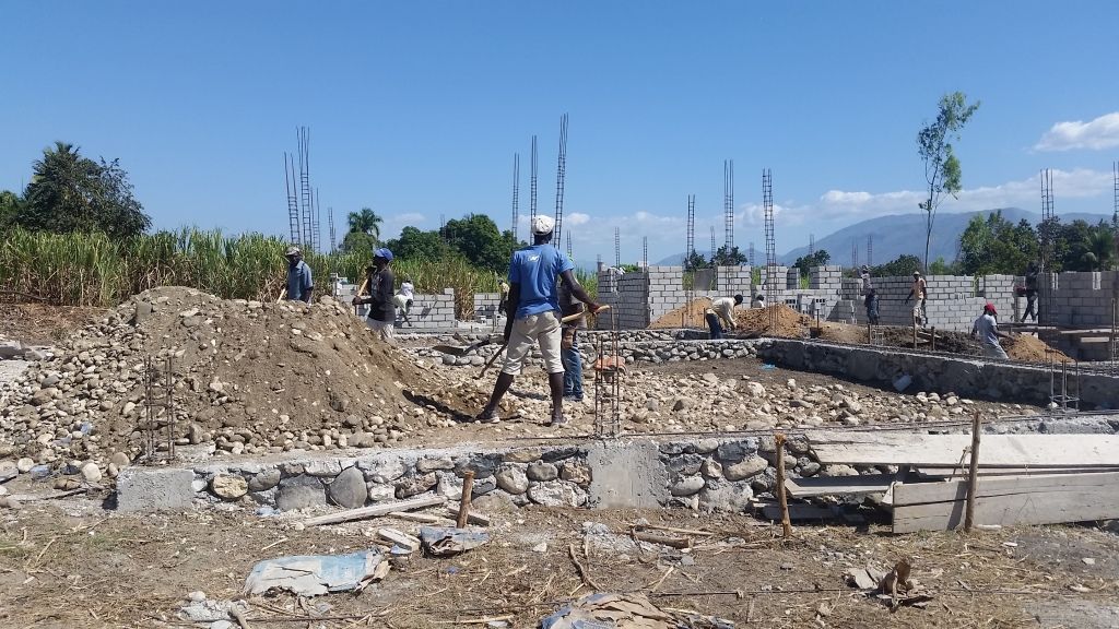 Construction site with workers building a foundation under a clear blue sky. 