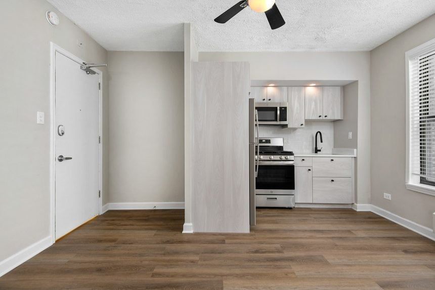 Part of living room and kitchen with white cabinets and stainless steel appliances