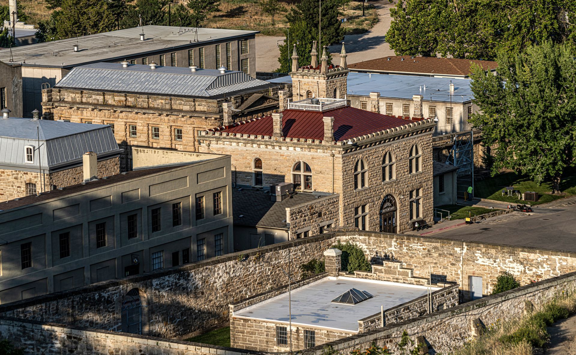 Aerial view of tan stone buildings with red roofs in a wooded hillside complex