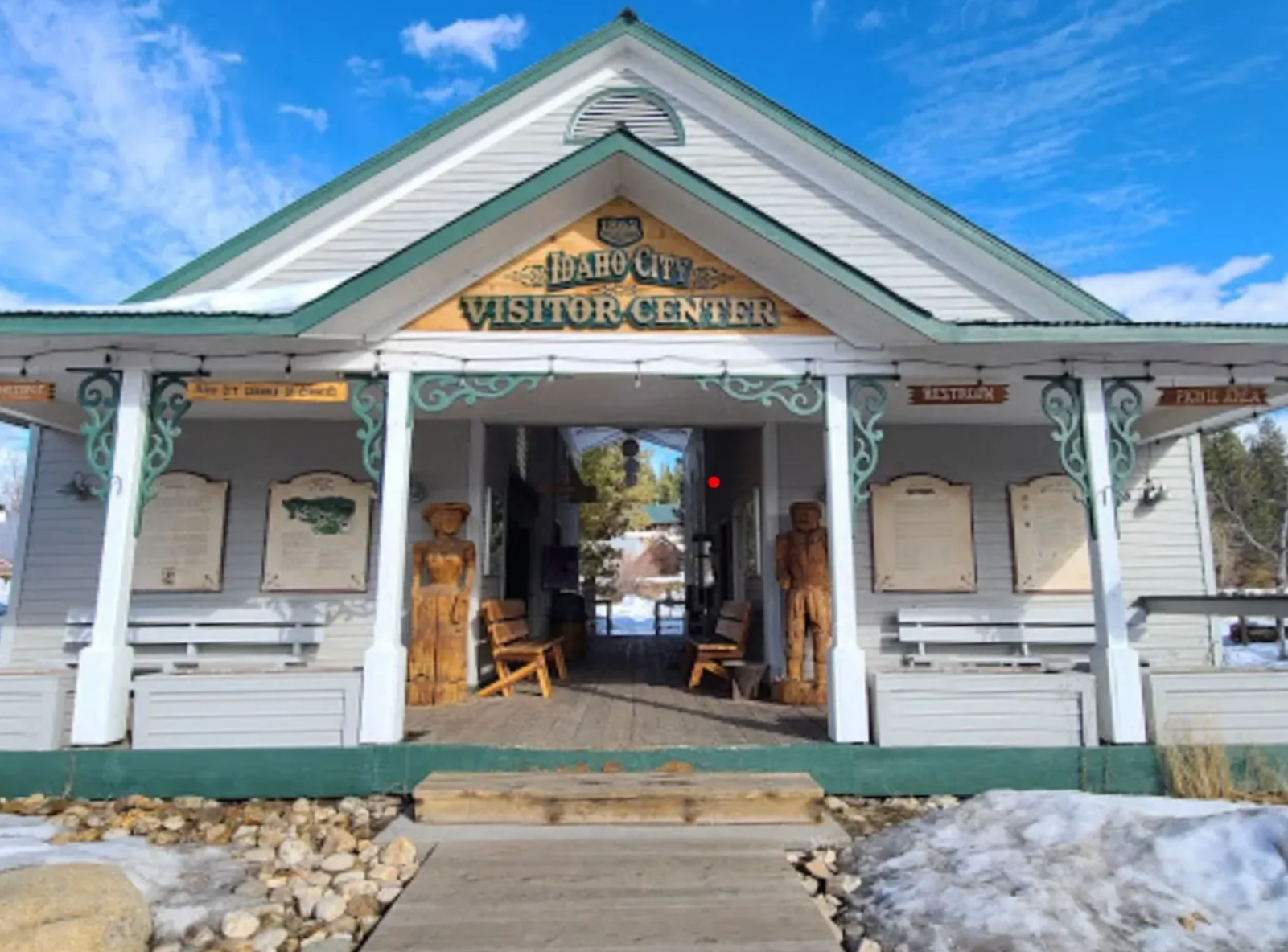 Visitor center with light grey siding, green trim, and wooden bear carvings.