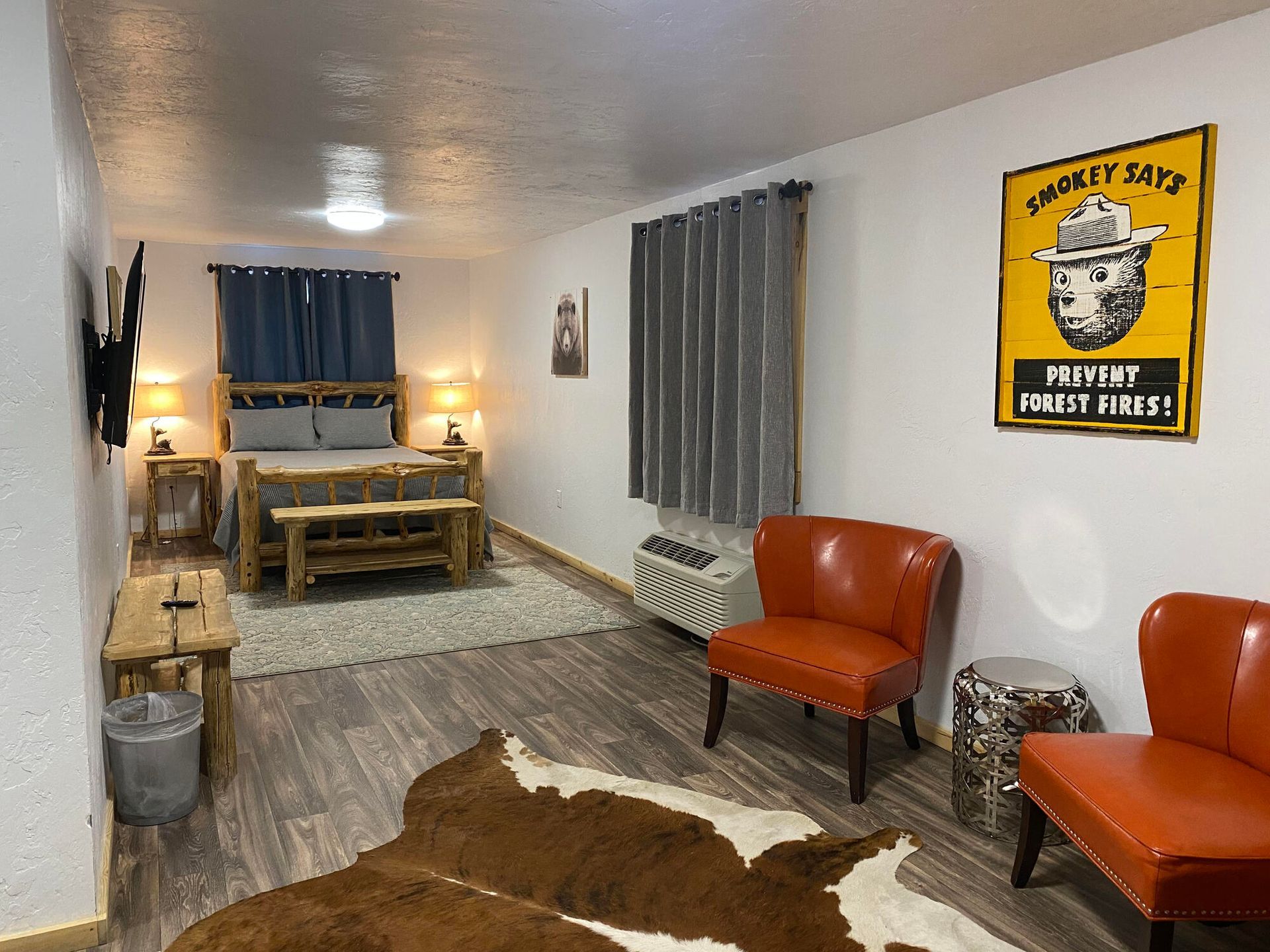 A room with a bed , chairs , a rug and a sign on the wall.