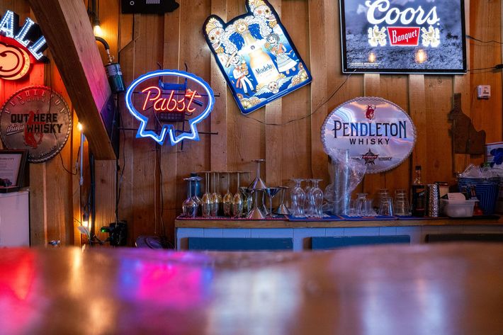A bar with a lot of neon signs hanging on the wall.