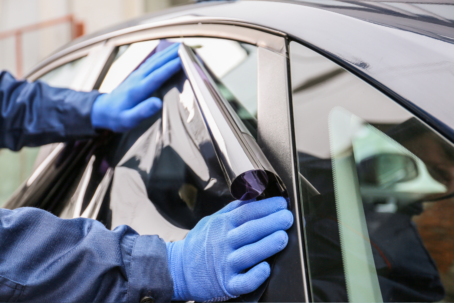 A person is applying tinted glass to a car window.
